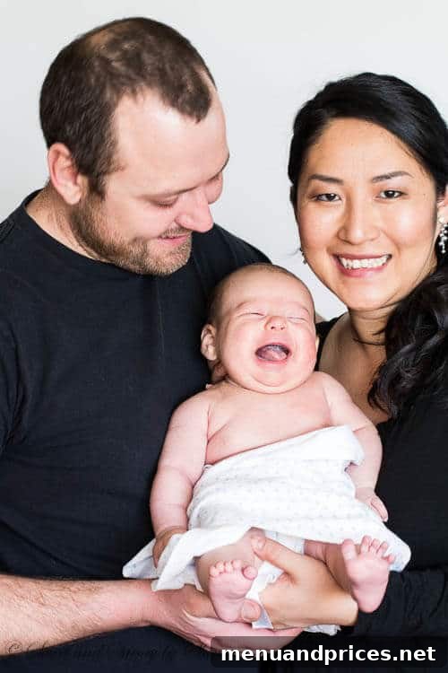 Eight Weeks of Wonder with Baby Grant 5 A happy family portrait with mom, dad, and baby Grant, all smiling joyfully and looking at the camera.