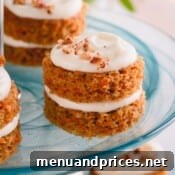 Close-up of fully assembled mini carrot cakes on a platter, garnished with candied pecans.