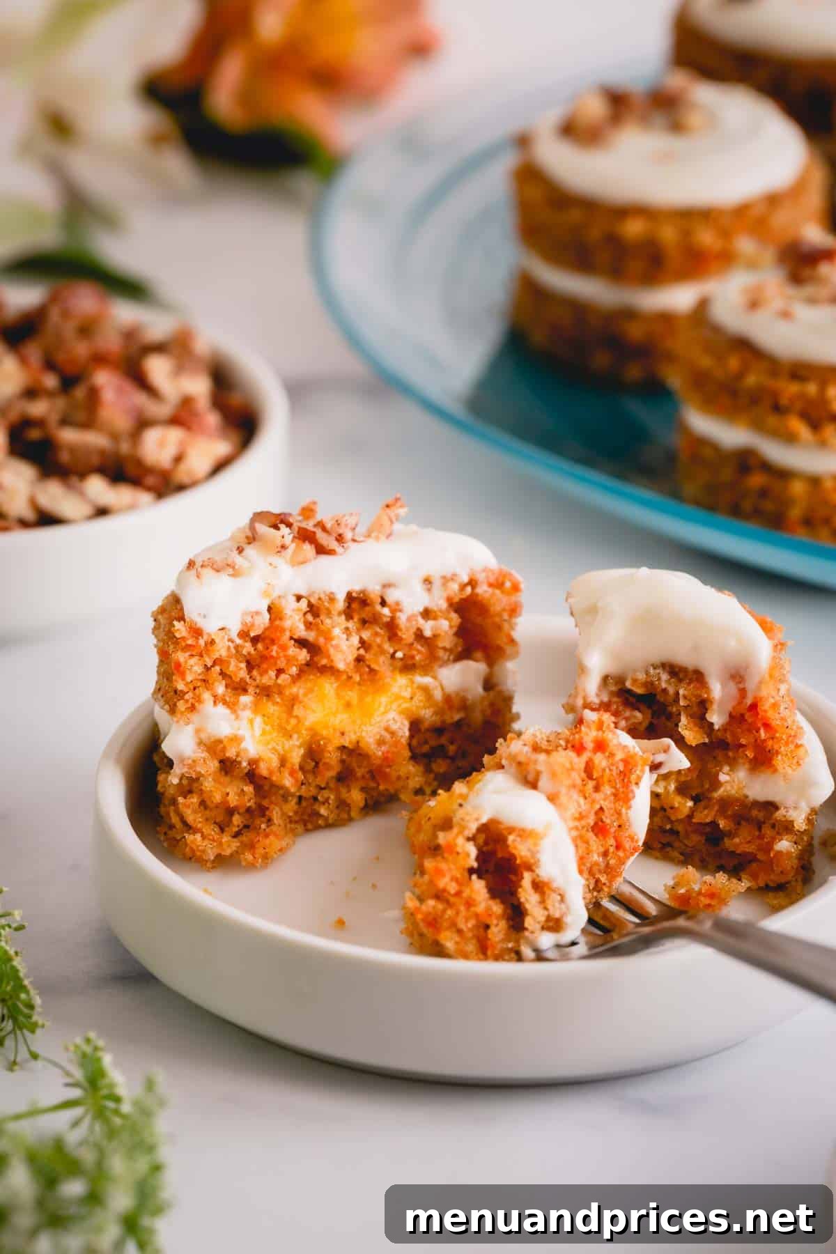 A mini carrot cake cut in half on a plate, showcasing its moist layers, creamy filling, and delightful texture.