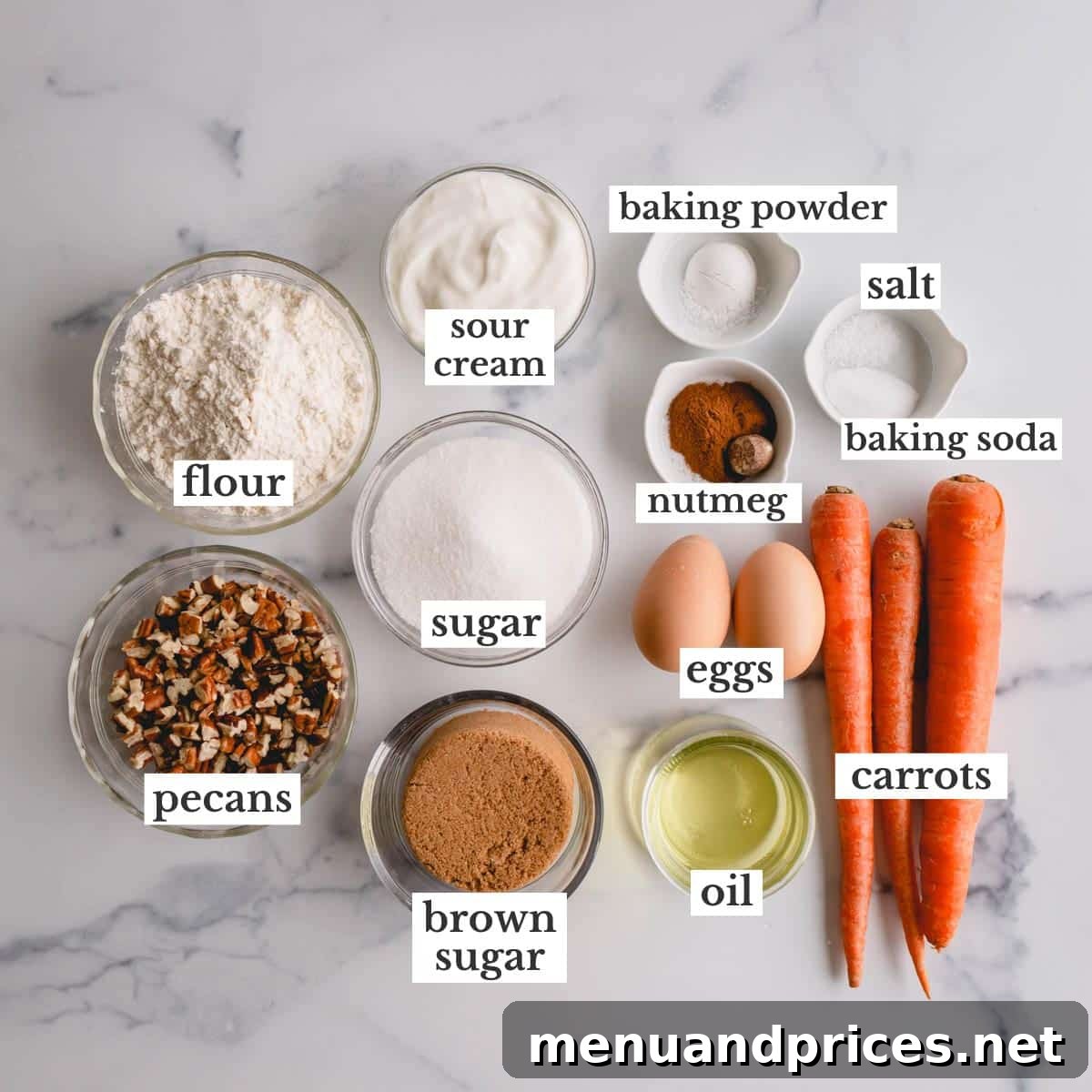 A selection of fresh ingredients for mini carrot cakes, including finely grated carrots, warm spices, flour, and liquid components.