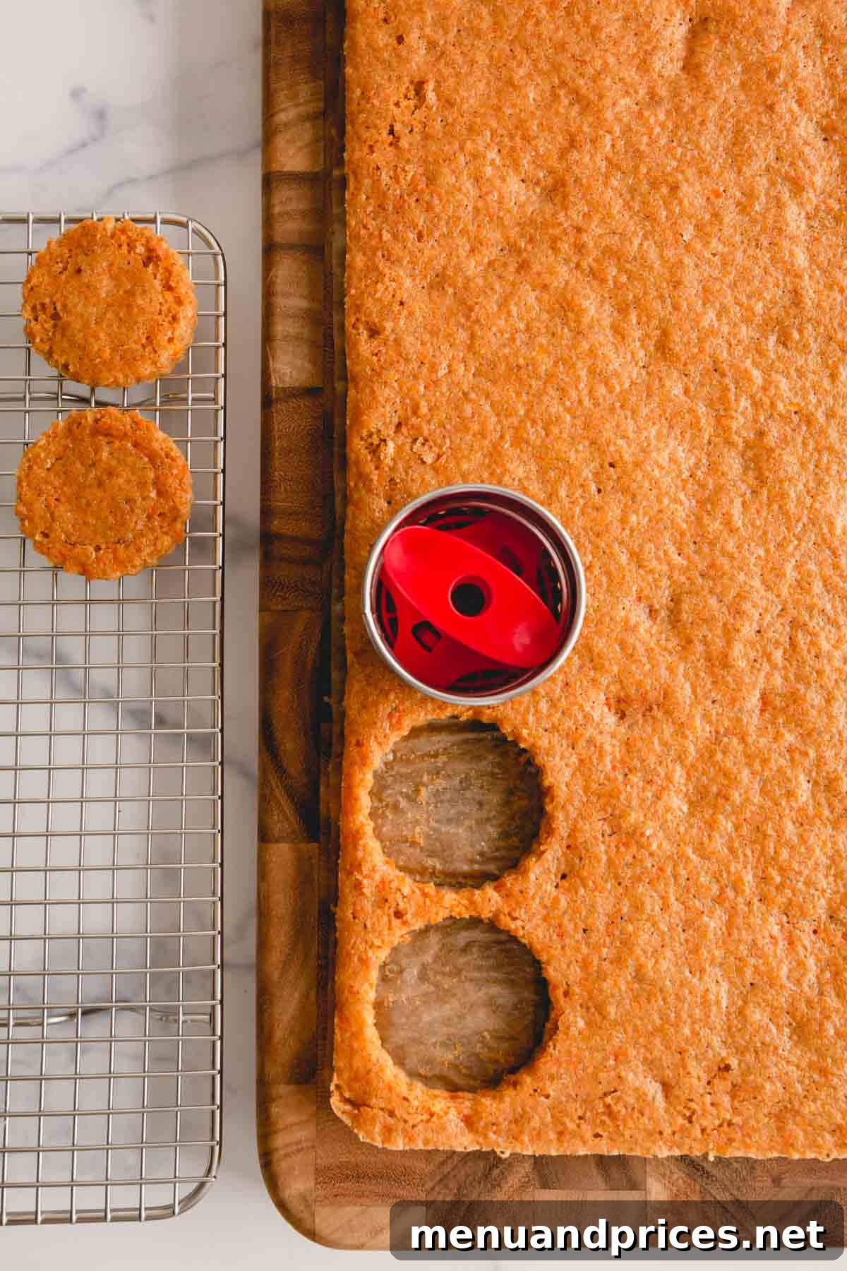 A round cookie cutter in action, precisely cutting cake circles from a large, baked carrot cake sheet.