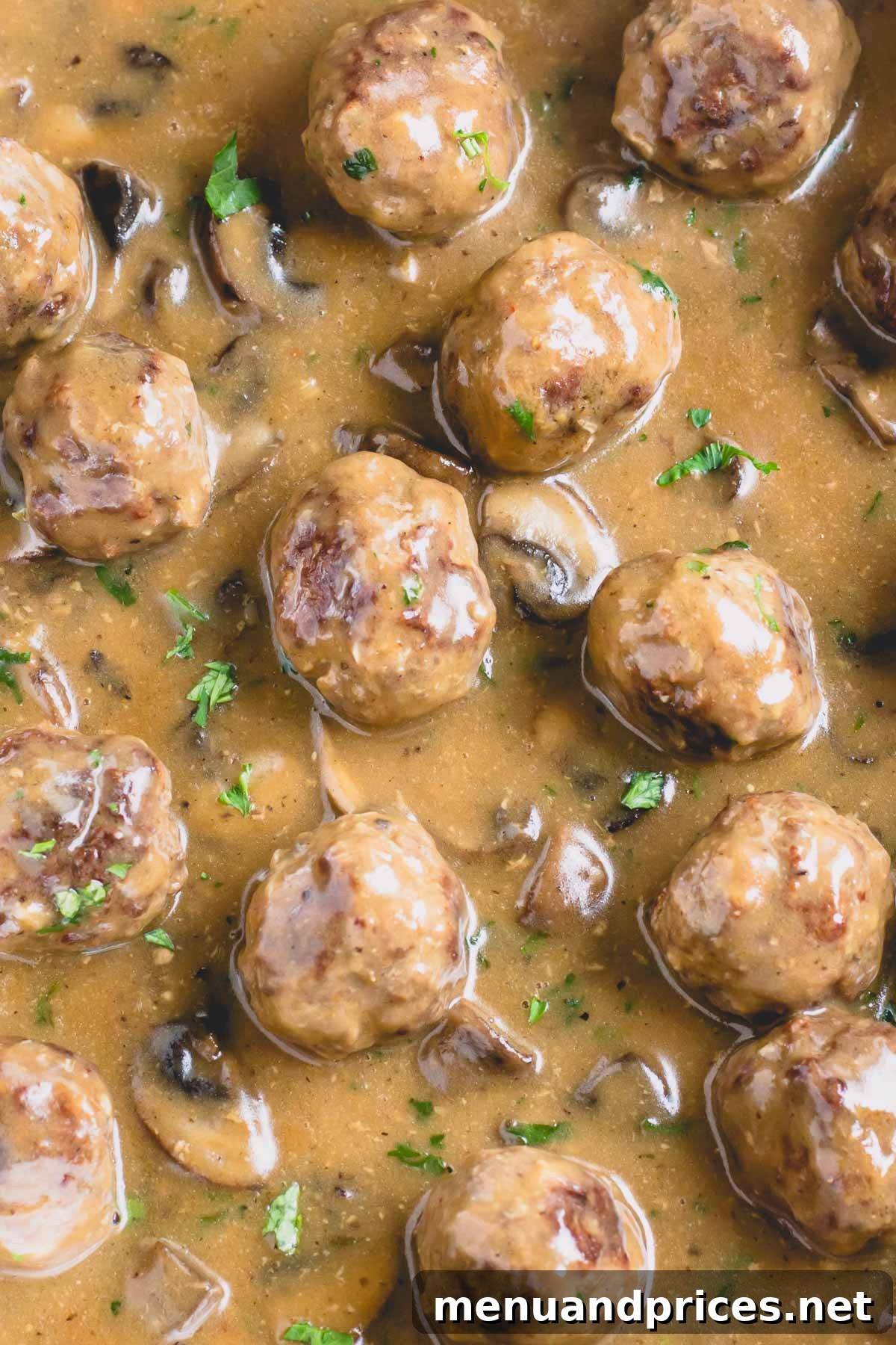 Beef meatballs in mushroom gravy topped with fresh green herbs, presented beautifully in a serving dish.