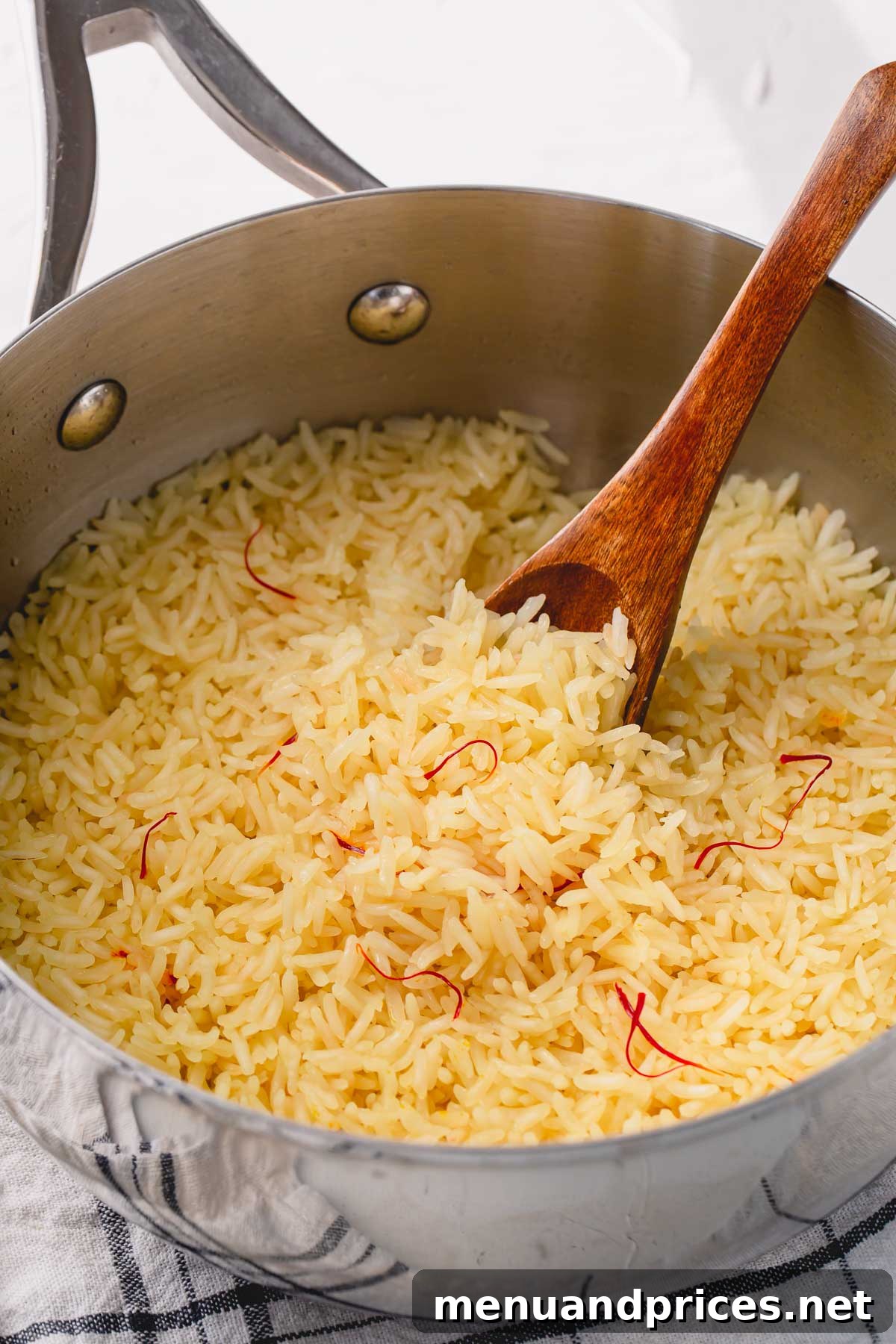 Sun-Drenched Saffron Rice 8 cooked saffron rice in skillet with wooden spoon