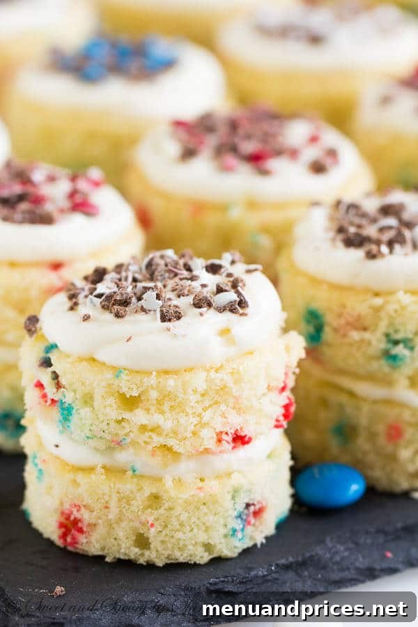 Overhead shot of two funfetti mini layer cakes on a rustic wooden surface, highlighting their individual size and decorative red, white, and blue toppings
