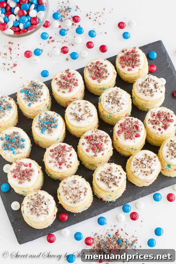 A beautifully arranged platter of funfetti mini layer cakes, some topped with crushed patriotic M&M's, creating a festive and inviting dessert display