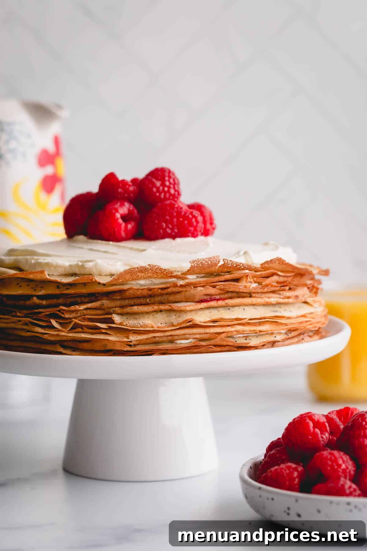 Zesty Lemon Raspberry Crepe Tower 7 A stunning top-down view of a lemon raspberry crepe cake garnished with fresh raspberries and a generous dollop of whipped cream, highlighting its elegant layers.
