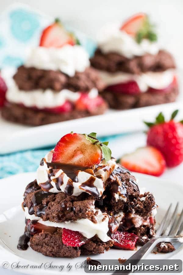 Velvet Berry Chocolate Stacks 3 A close-up shot of an assembled chocolate strawberry shortcake with a generous dollop of whipped cream and sliced strawberries