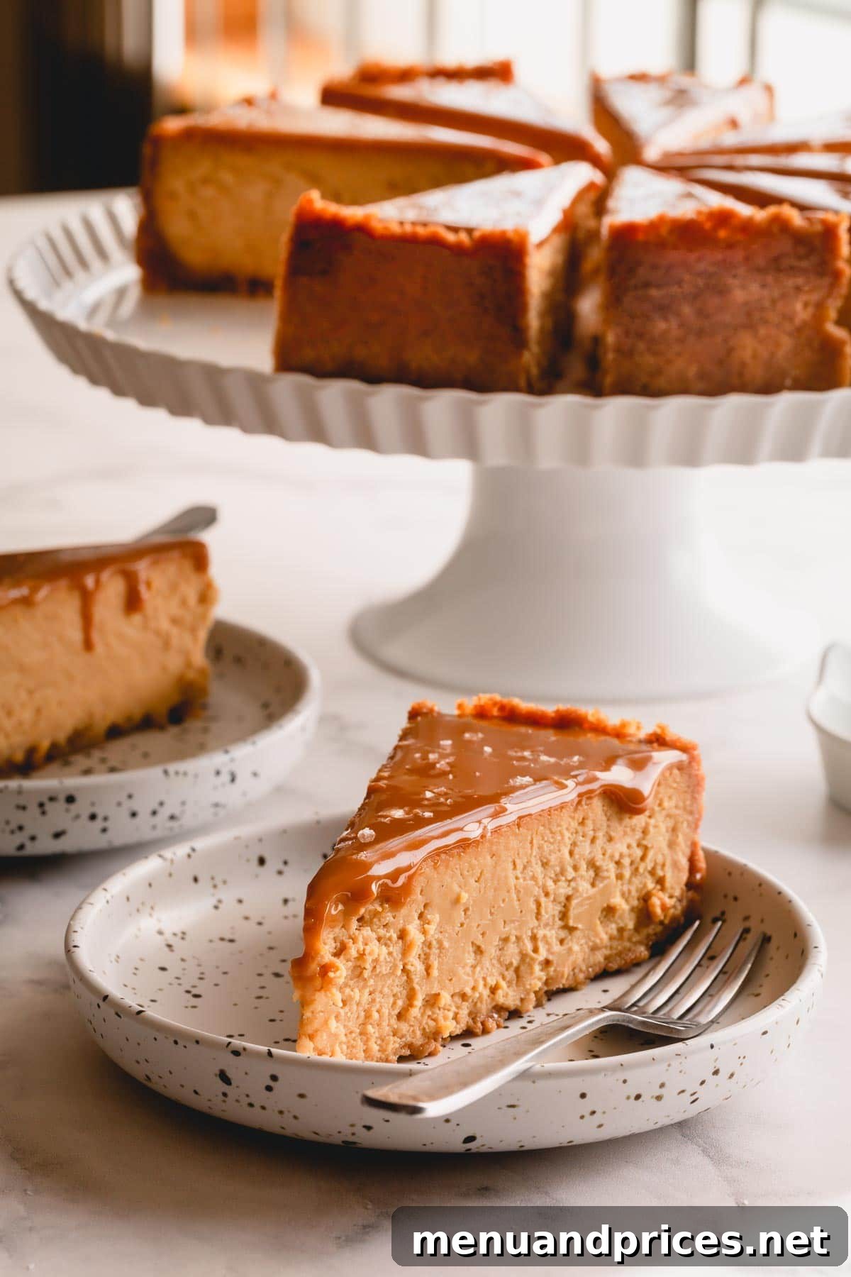 A perfectly sliced piece of Dulce de Leche Cheesecake on a small white plate, showcasing its creamy texture and golden topping.