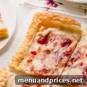 A slice of strawberry cheesecake tart with a fork, showing the creamy texture and flaky crust.