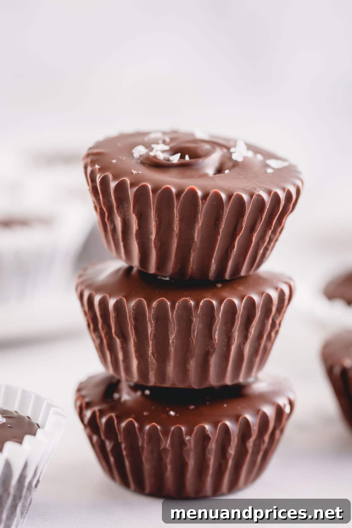 Gourmet Chocolate Caramel Indulgence 2 Three decadent chocolate cups, each topped with a delicate sprinkle of salt flakes, elegantly stacked atop one another.