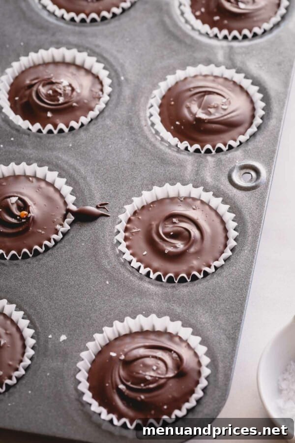Gourmet Chocolate Caramel Indulgence 6 Several chocolate cups, each topped with delicate salt flakes, neatly arranged in a mini muffin pan.