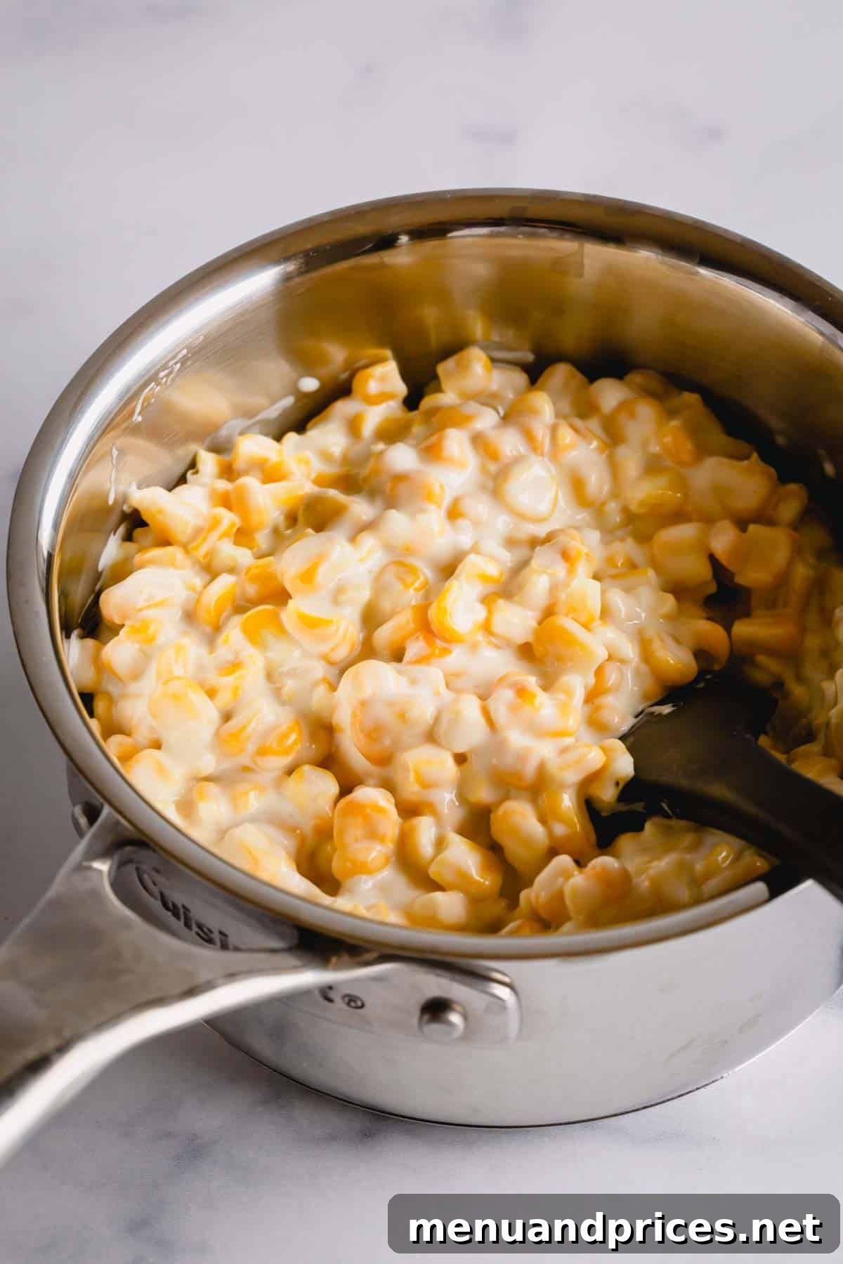 Effortless Creamed Corn 4 Creamed corn simmering in a saucepan with a black spatula, ready to be served.