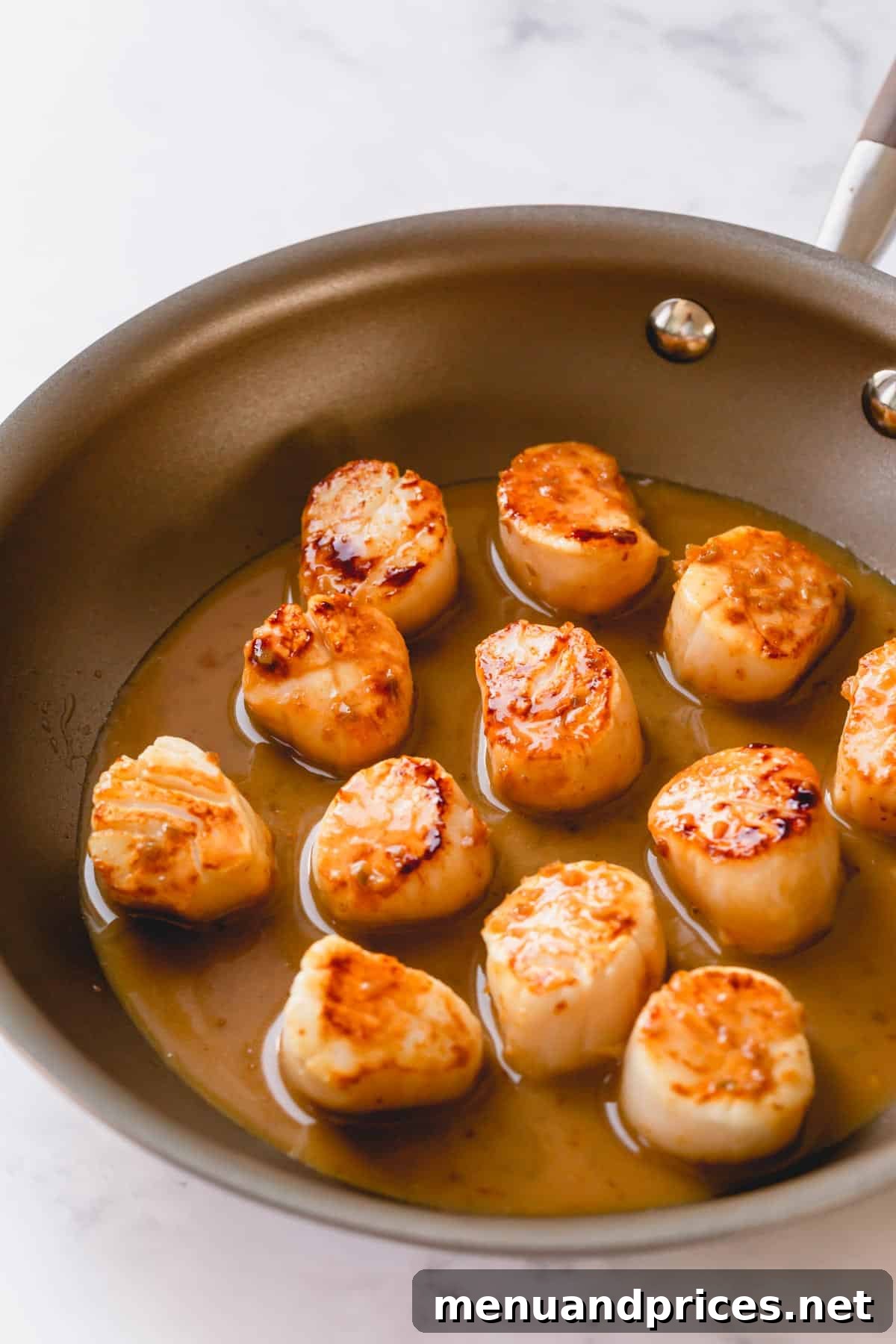 Tequila Lime Glazed Scallop Pasta 3 Close-up view of golden-brown seared scallops bathing in a vibrant tequila lime sauce within a skillet, showcasing the delicious glaze.