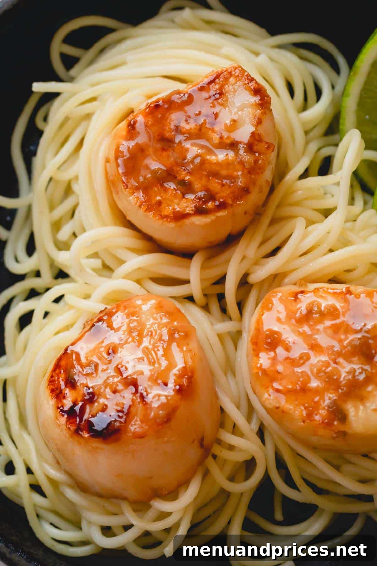 Tequila Lime Glazed Scallop Pasta 7 A close-up of caramelized, golden-brown scallops artfully arranged over a generous serving of spaghetti, ready to be enjoyed.