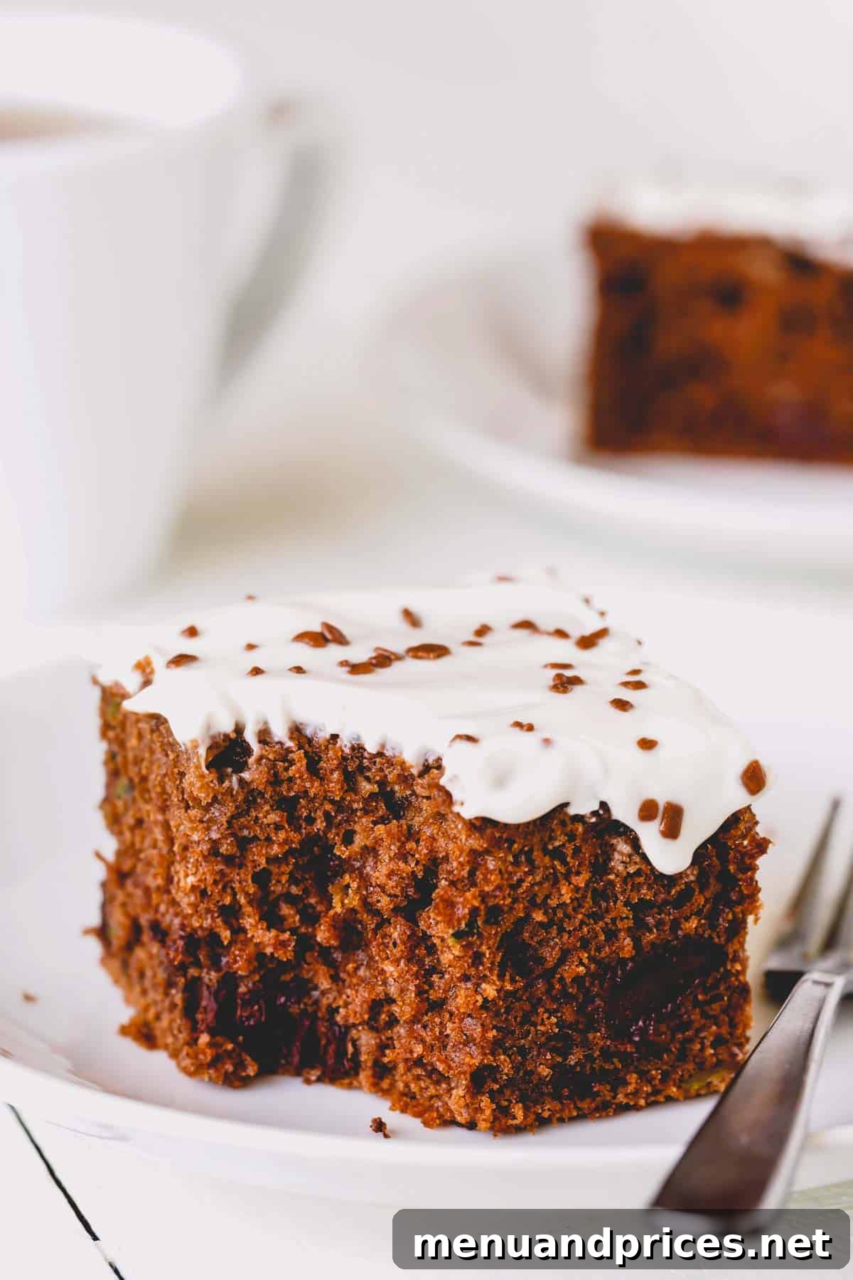 Fudgy Chocolate Zucchini Sheet Cake 2 A square slice of double chocolate zucchini cake with a bite missing, showcasing its rich, dark interior and creamy frosting.