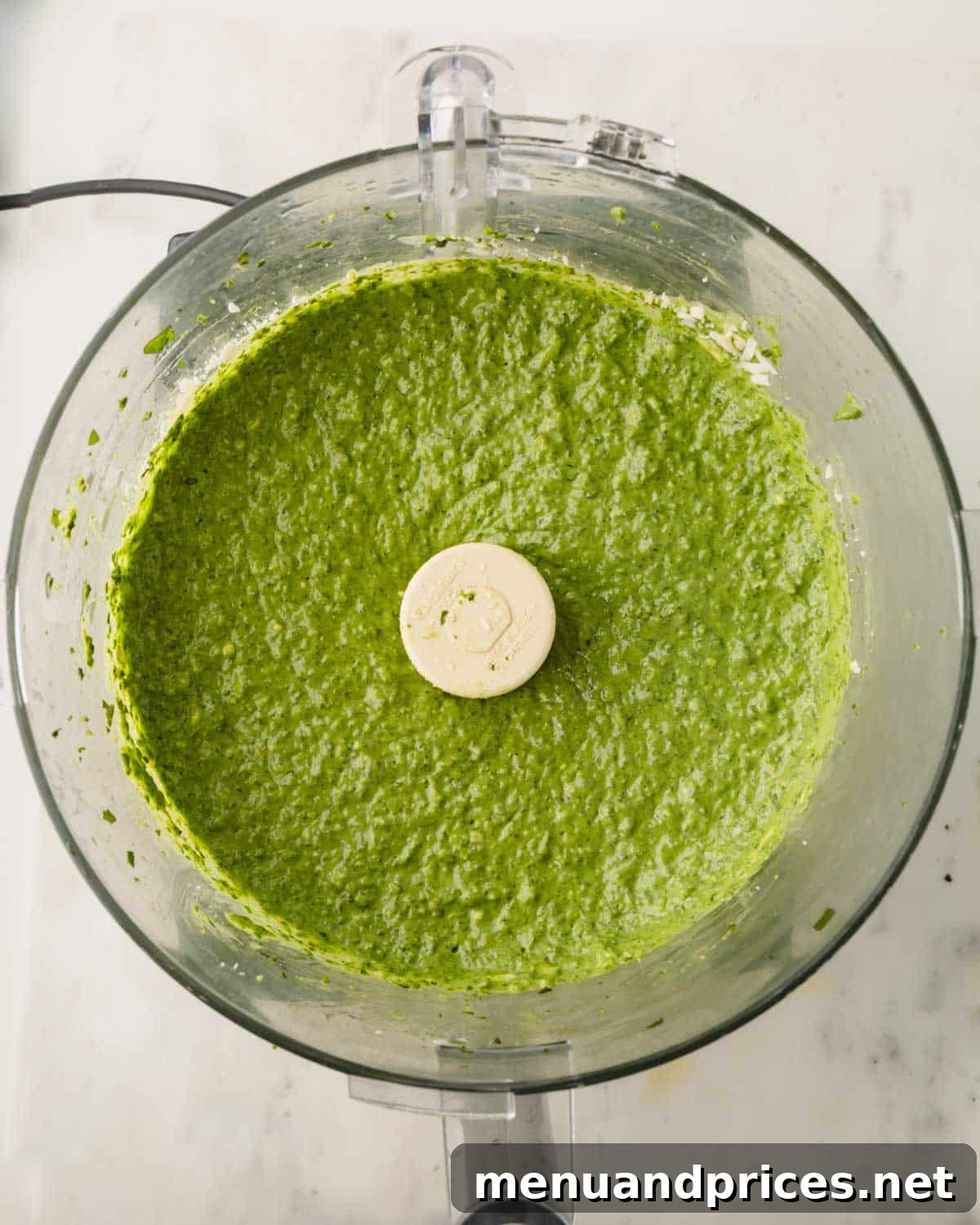 Big Batch Basil Pesto: A Freezer-Friendly Recipe 13 The final, perfectly blended basil pesto in a food processor, showcasing its smooth, vibrant green texture.