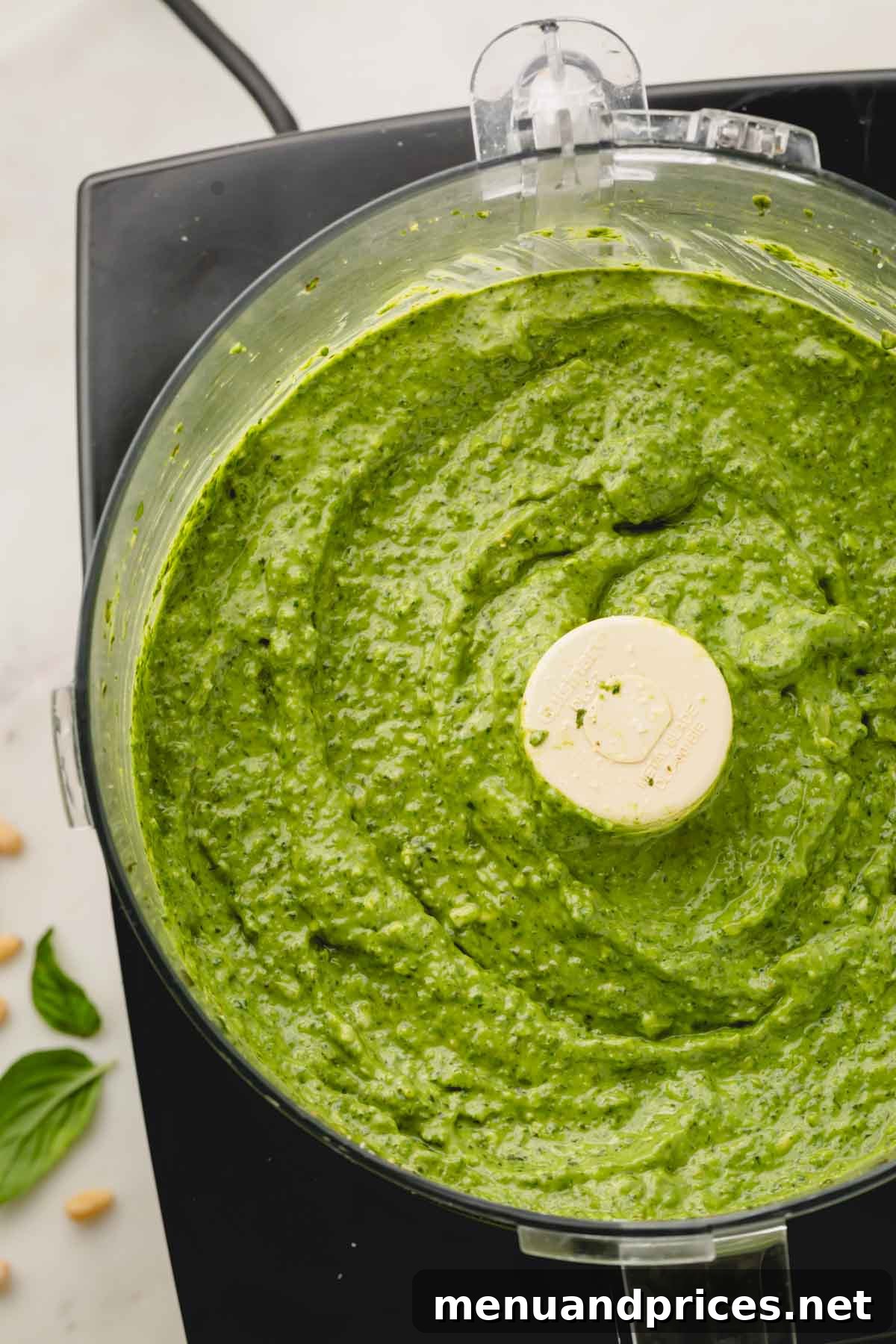 Big Batch Basil Pesto: A Freezer-Friendly Recipe 3 Fresh basil pesto being processed in a food processor, showcasing its creamy green texture.