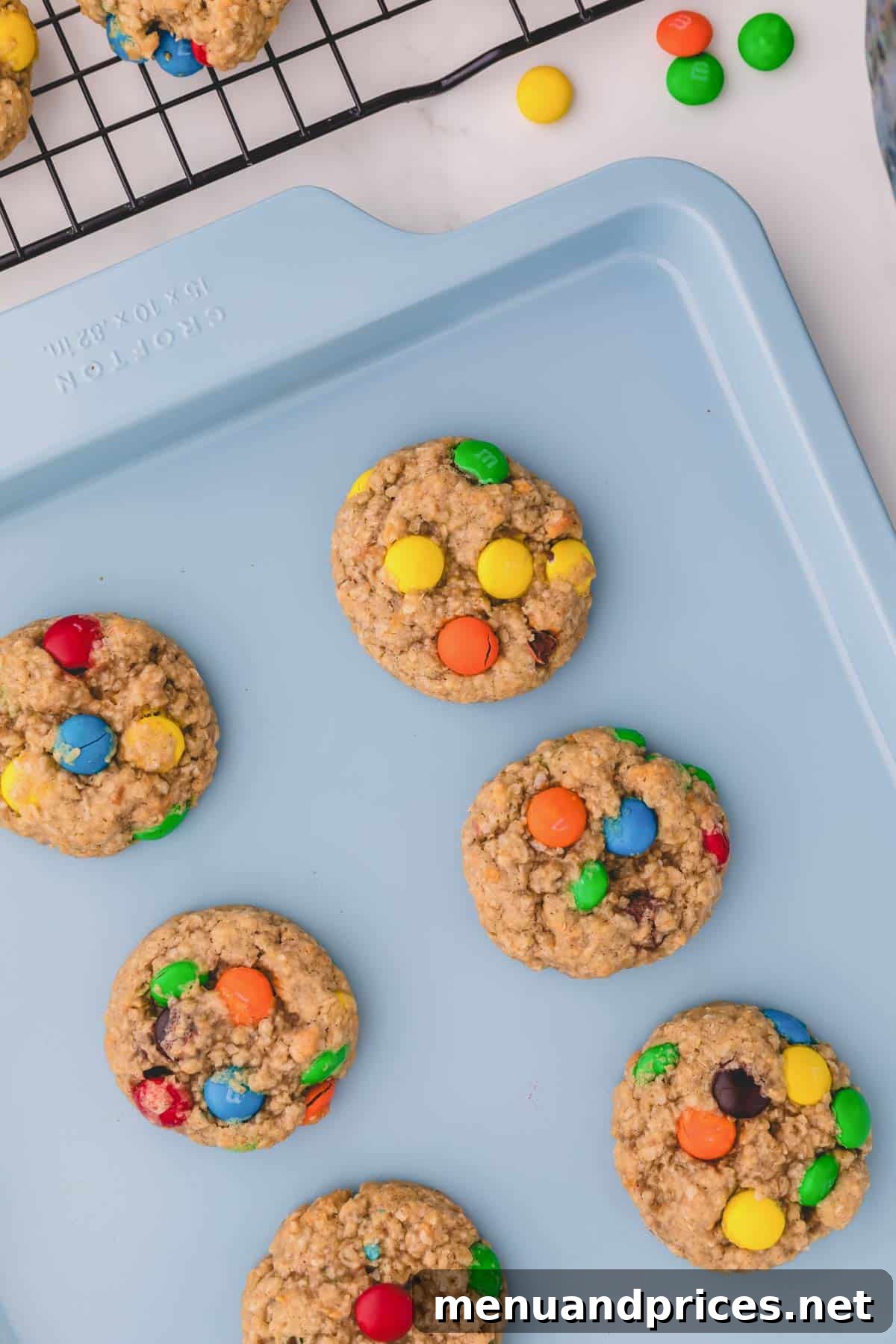 Freshly baked apple cinnamon oatmeal cookies with golden-brown edges and soft centers, cooling on a sheet pan just out of the oven.