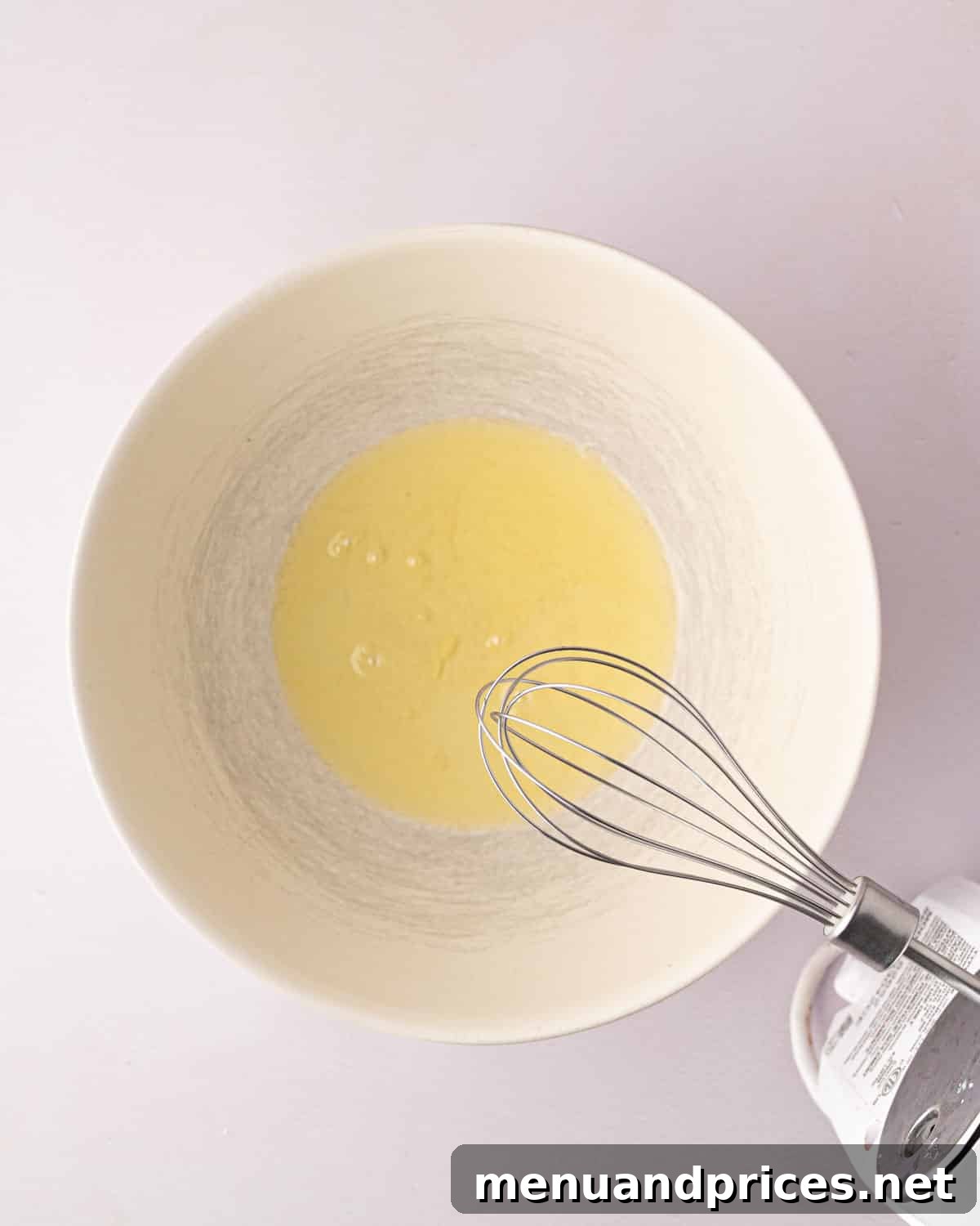Zesty Lemon Dream 12 A hand mixer beater over a white bowl with egg whites.