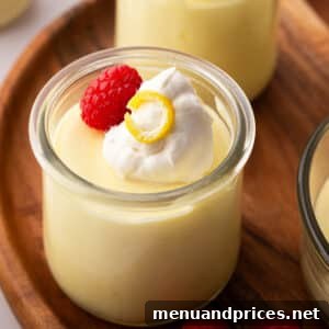 Lemon mousse in a small glass jar on a wooden board.