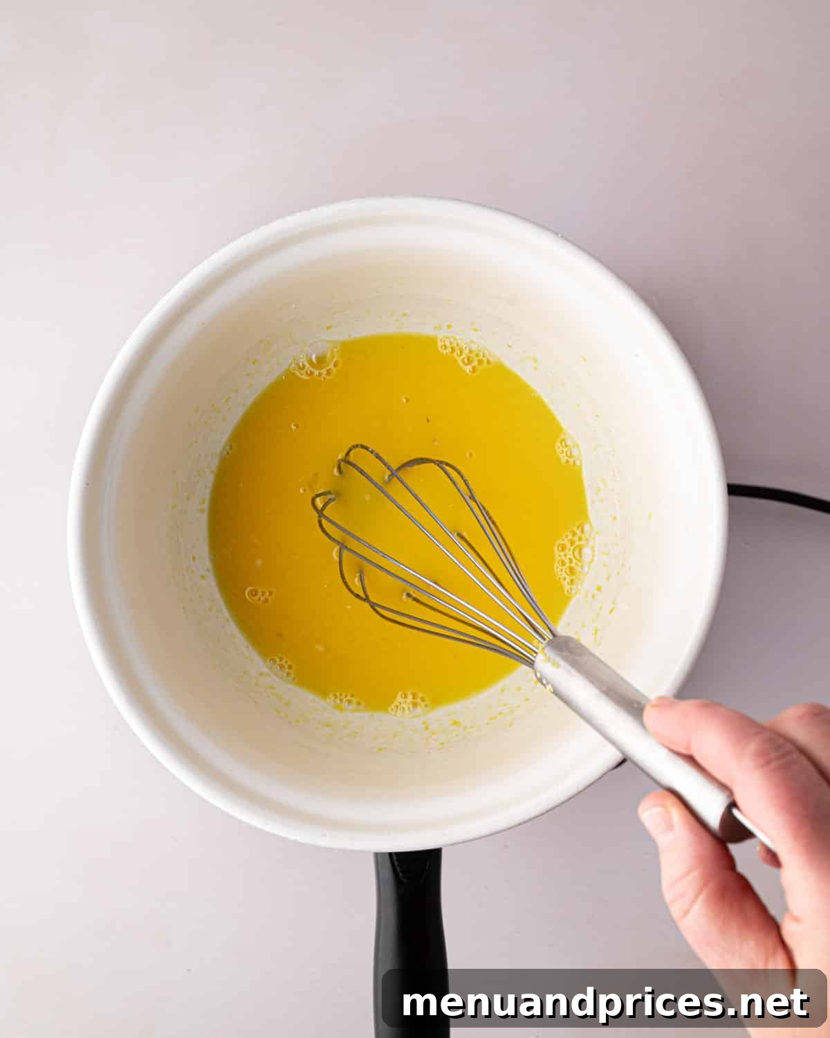 Zesty Lemon Dream 7 A white bowl with lemon juice and sugar. A hand holding a whisk.