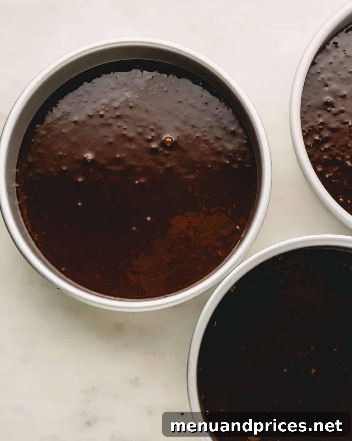 German chocolate cake batter neatly poured into three round cake pans, ready for baking.