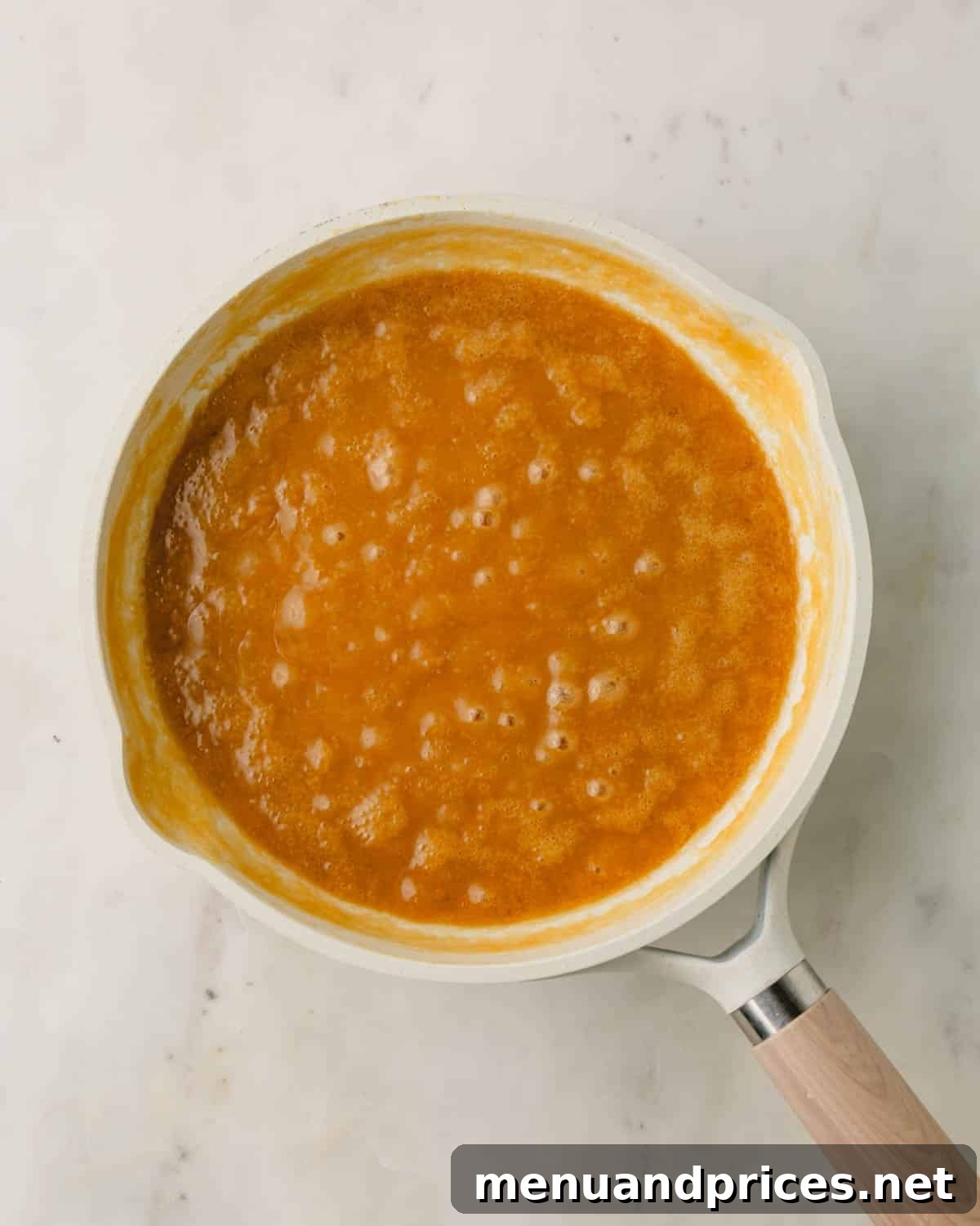 A saucepan on a stovetop showing the coconut pecan frosting base simmering and thickening.