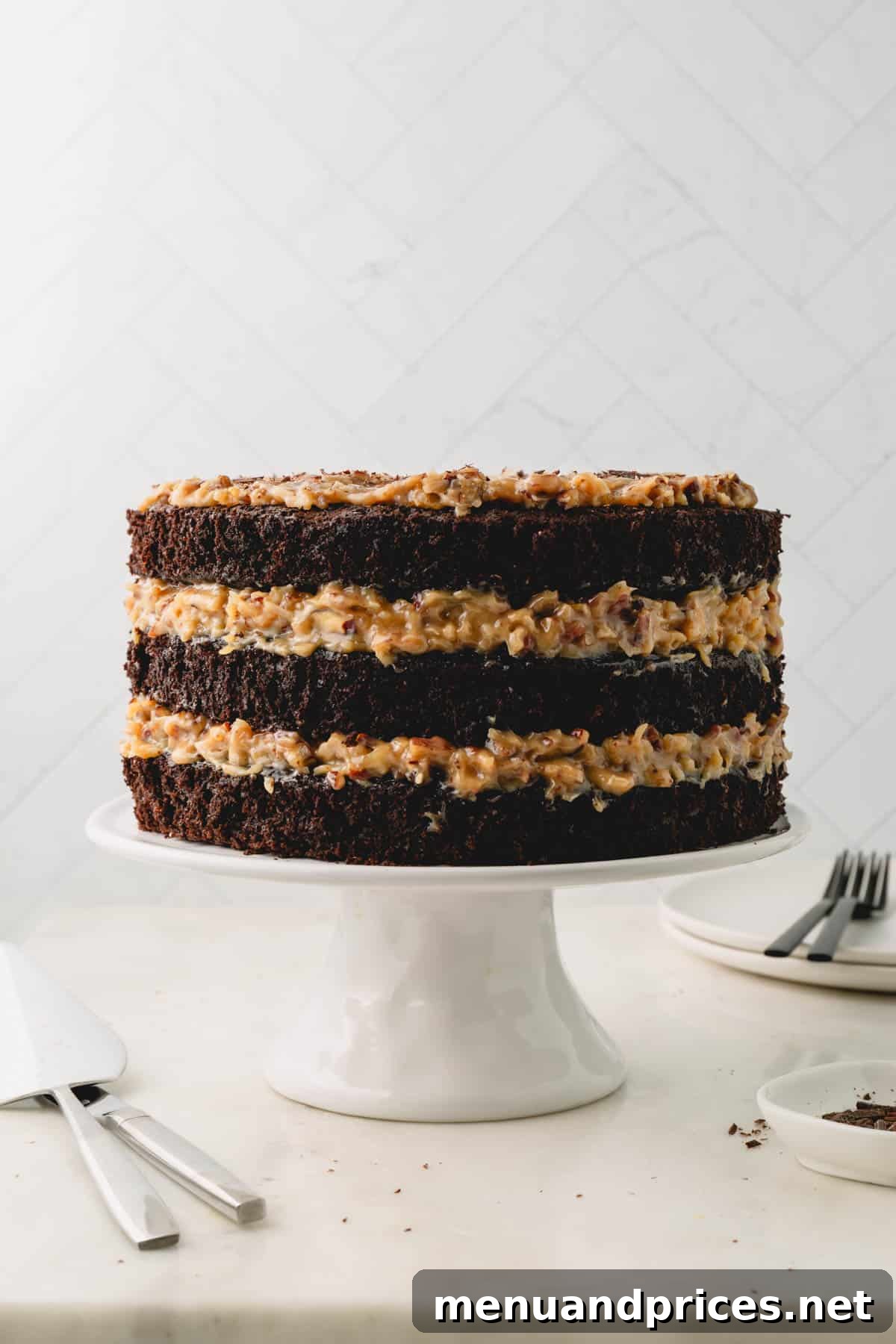 A beautifully assembled three-layer German chocolate cake on a white cake pedestal, showcasing its distinct layers of cake and frosting.