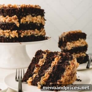 A slice of German chocolate cake on a white plate with a cake on a pedestal and another slice in the background.