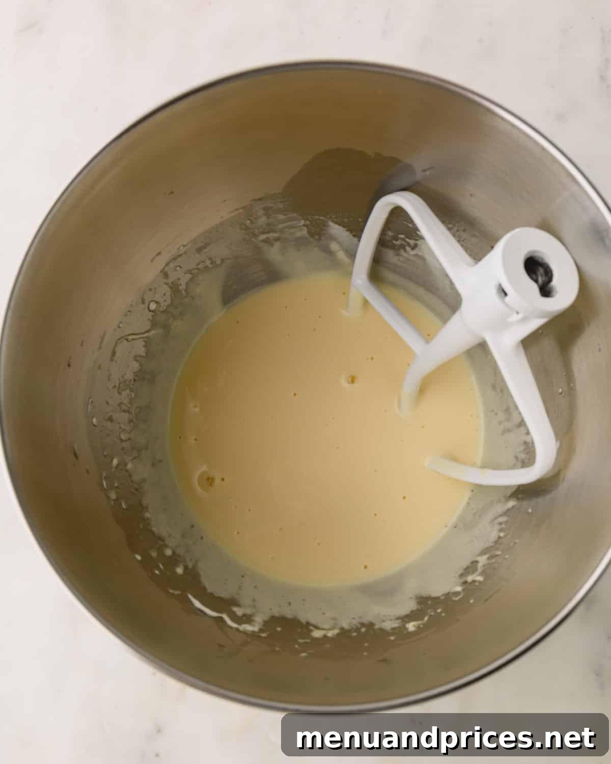 The wet ingredients for German chocolate cake after being mixed with a paddle attachment, appearing smooth and homogenous.