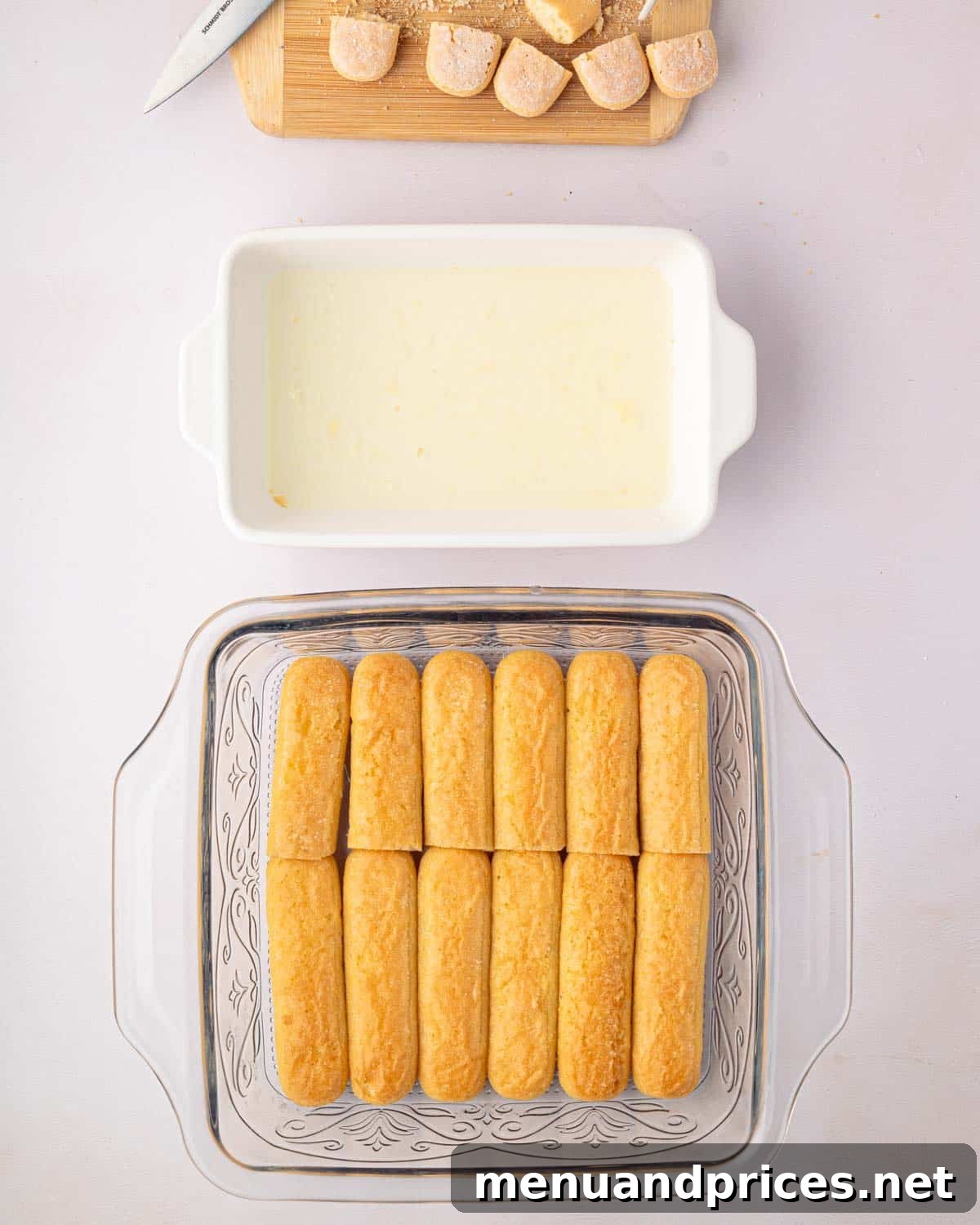 Bright Citrus Tiramisu 16 A clear glass baking dish with a single layer of limoncello-soaked ladyfingers at the bottom, alongside the syrup bowl.