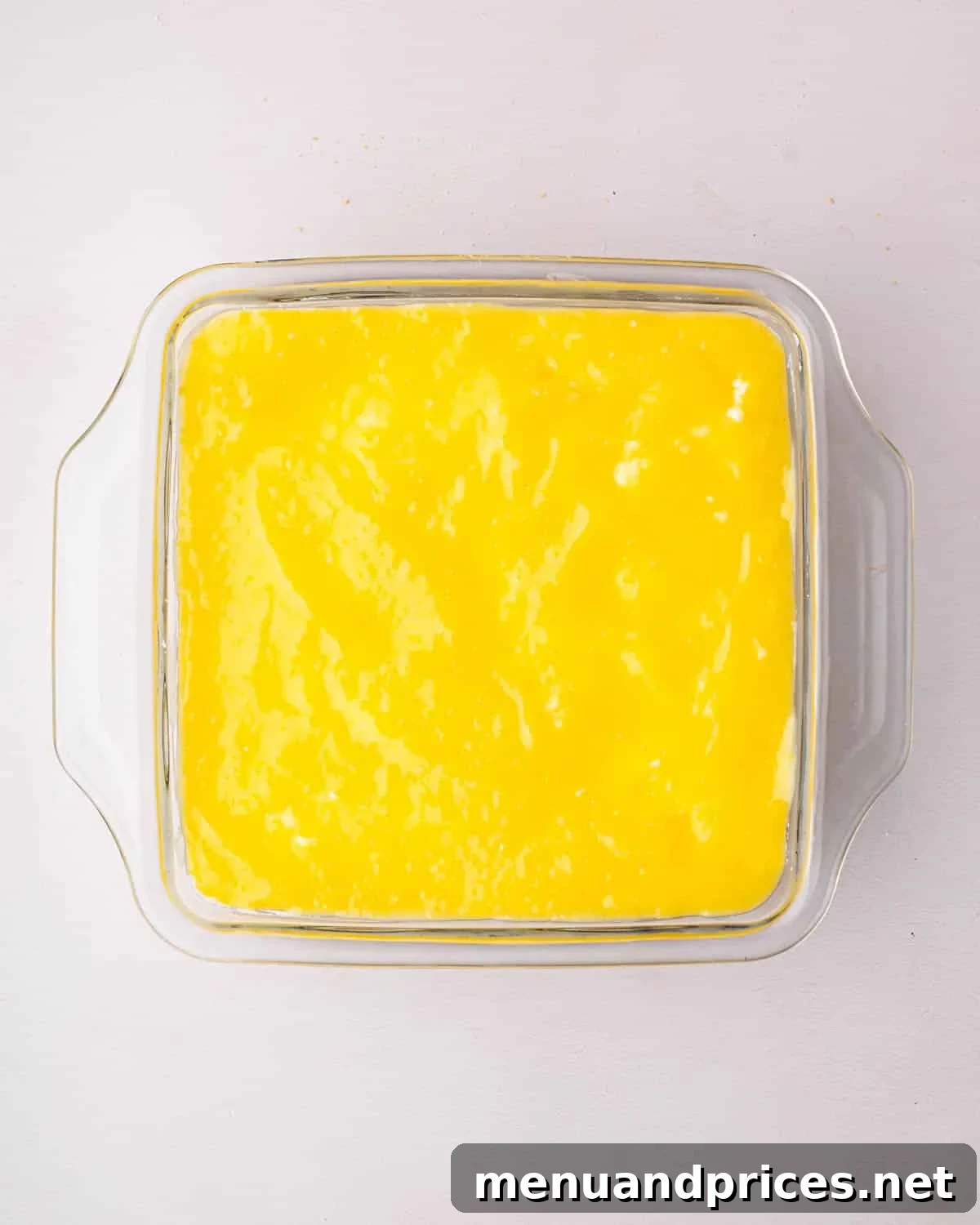 Bright Citrus Tiramisu 22 The finished lemon tiramisu in a glass baking dish, with the top layer of smooth lemon curd spread evenly, ready for chilling.