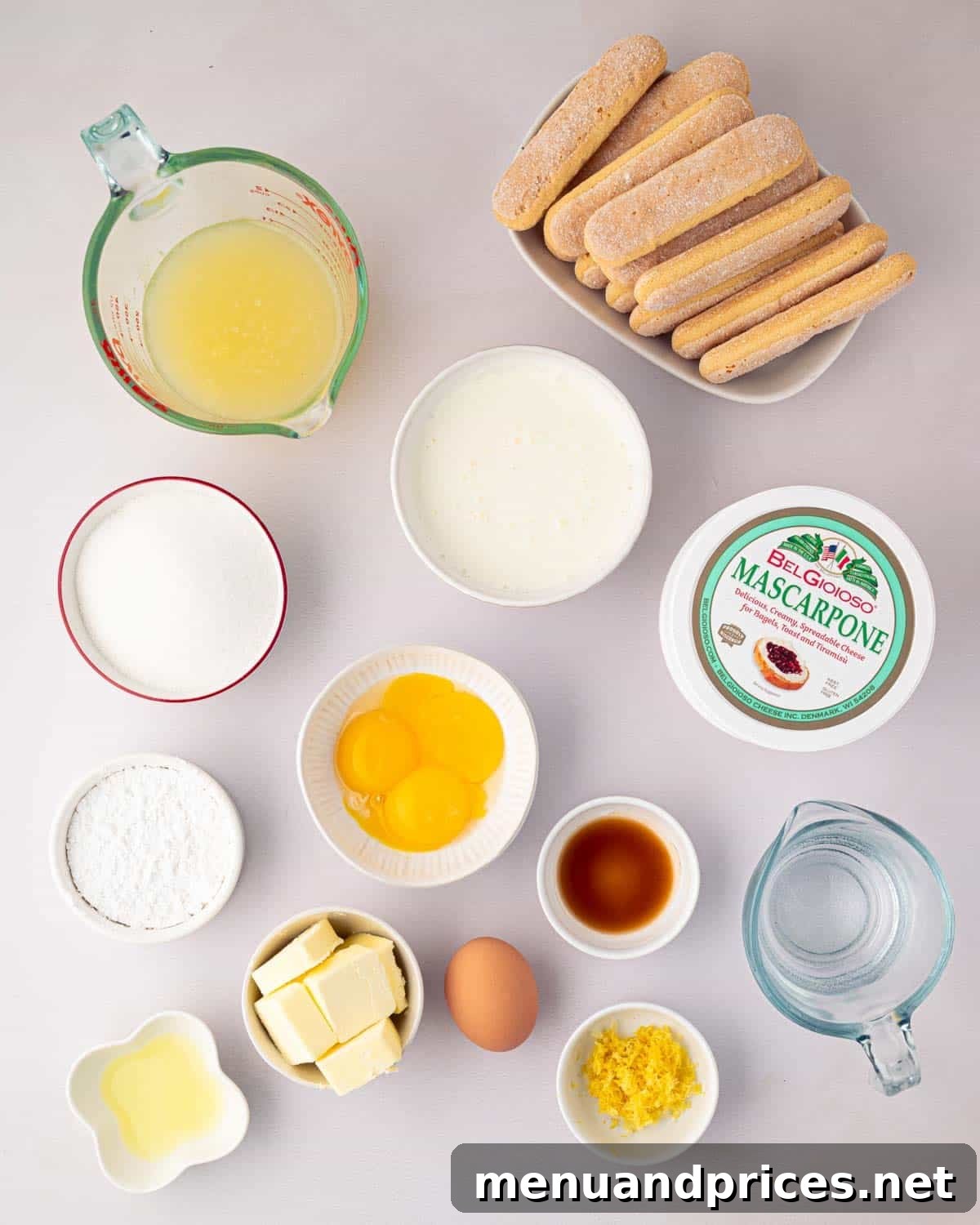 Bright Citrus Tiramisu 4 All the fresh ingredients laid out for making lemon tiramisu, including lemons, eggs, mascarpone, butter, and ladyfingers, on a rustic wooden surface.