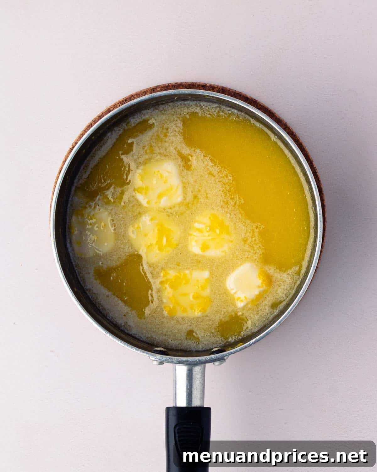 Bright Citrus Tiramisu 7 Butter being whisked into the hot lemon curd mixture in a black saucepan.