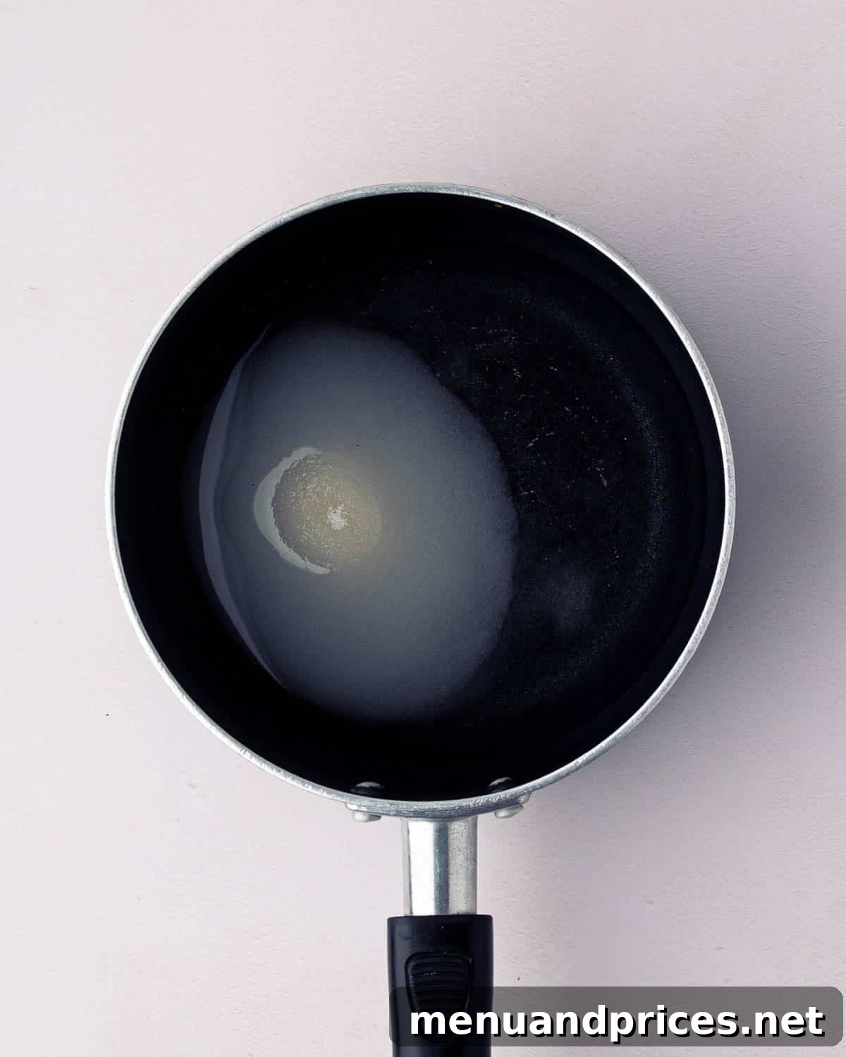 Bright Citrus Tiramisu 9 A small black skillet with water and sugar, beginning to melt and combine into a simple syrup.