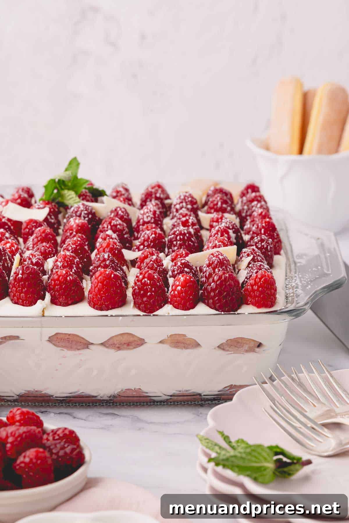 Side image of a slice of raspberry tiramisu in a glass baking dish, showcasing its vibrant layers.
