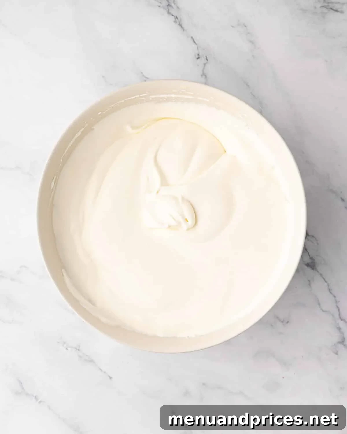 The finished, smooth, and airy mascarpone cream in a white bowl.