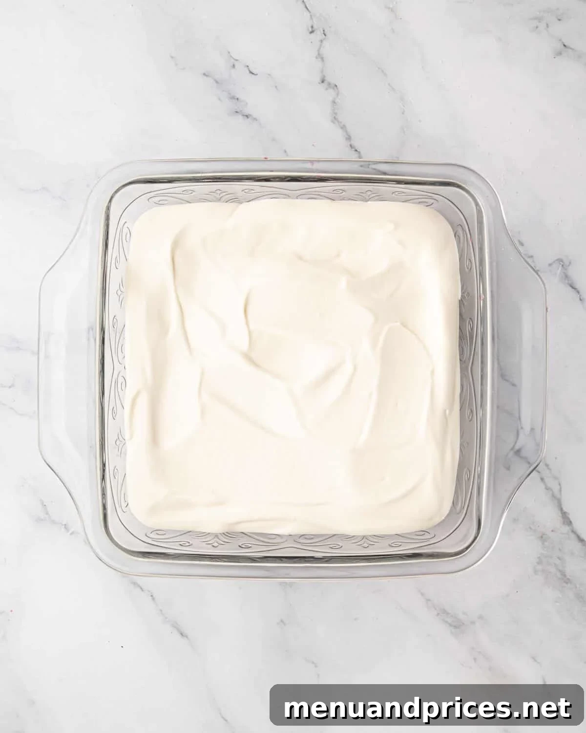 The first layer of creamy mascarpone spread over the raspberry-soaked ladyfingers.