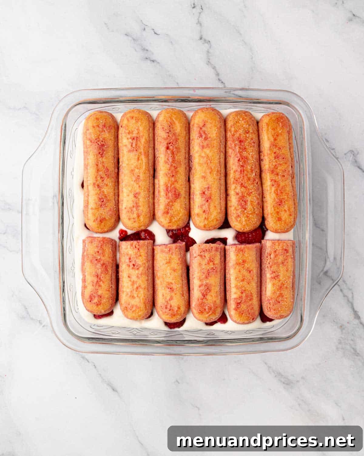 The second layer of raspberry-soaked ladyfingers placed over the fruit and cream.