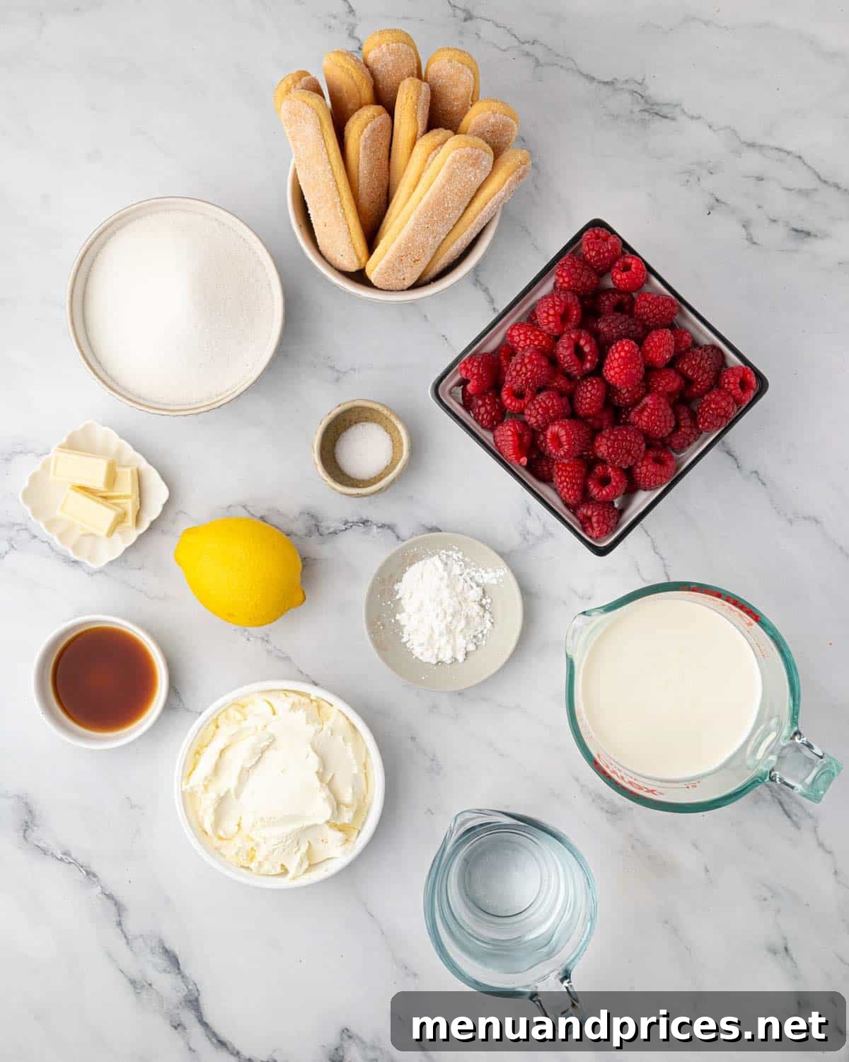 A display of fresh ingredients for raspberry tiramisu, including raspberries, mascarpone, and ladyfingers.