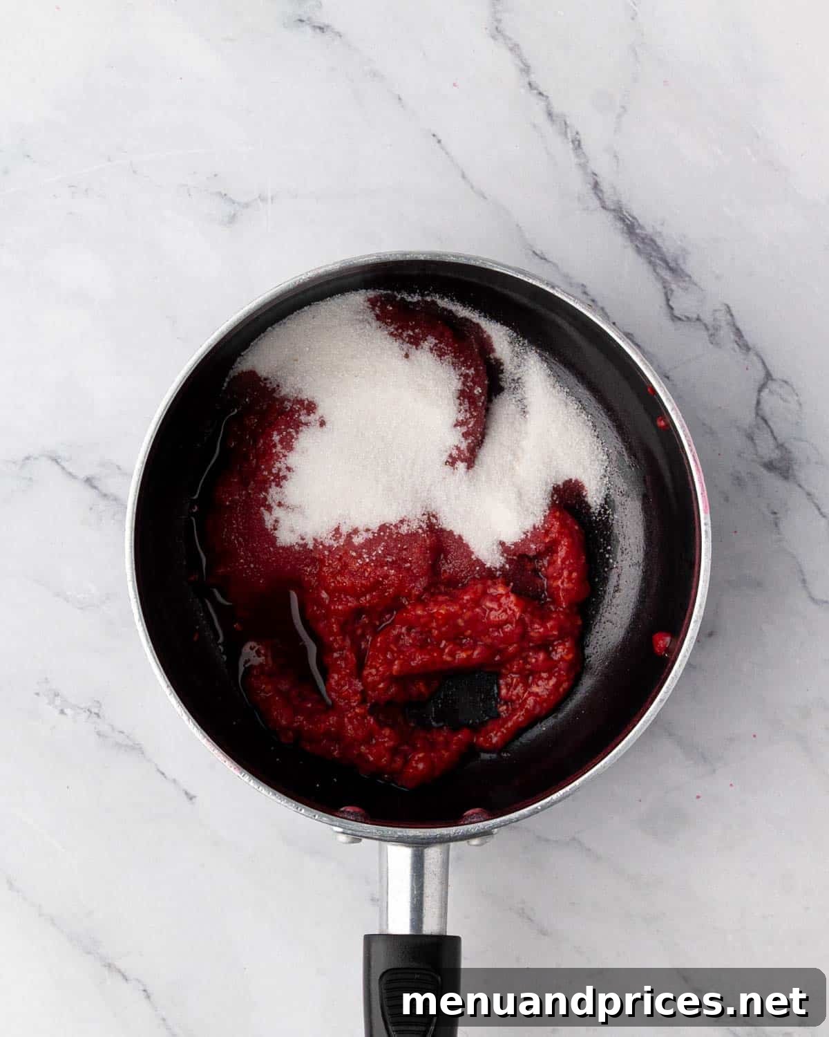 Raspberry pulp with sugar and salt in a saucepan, ready to be cooked into compote.