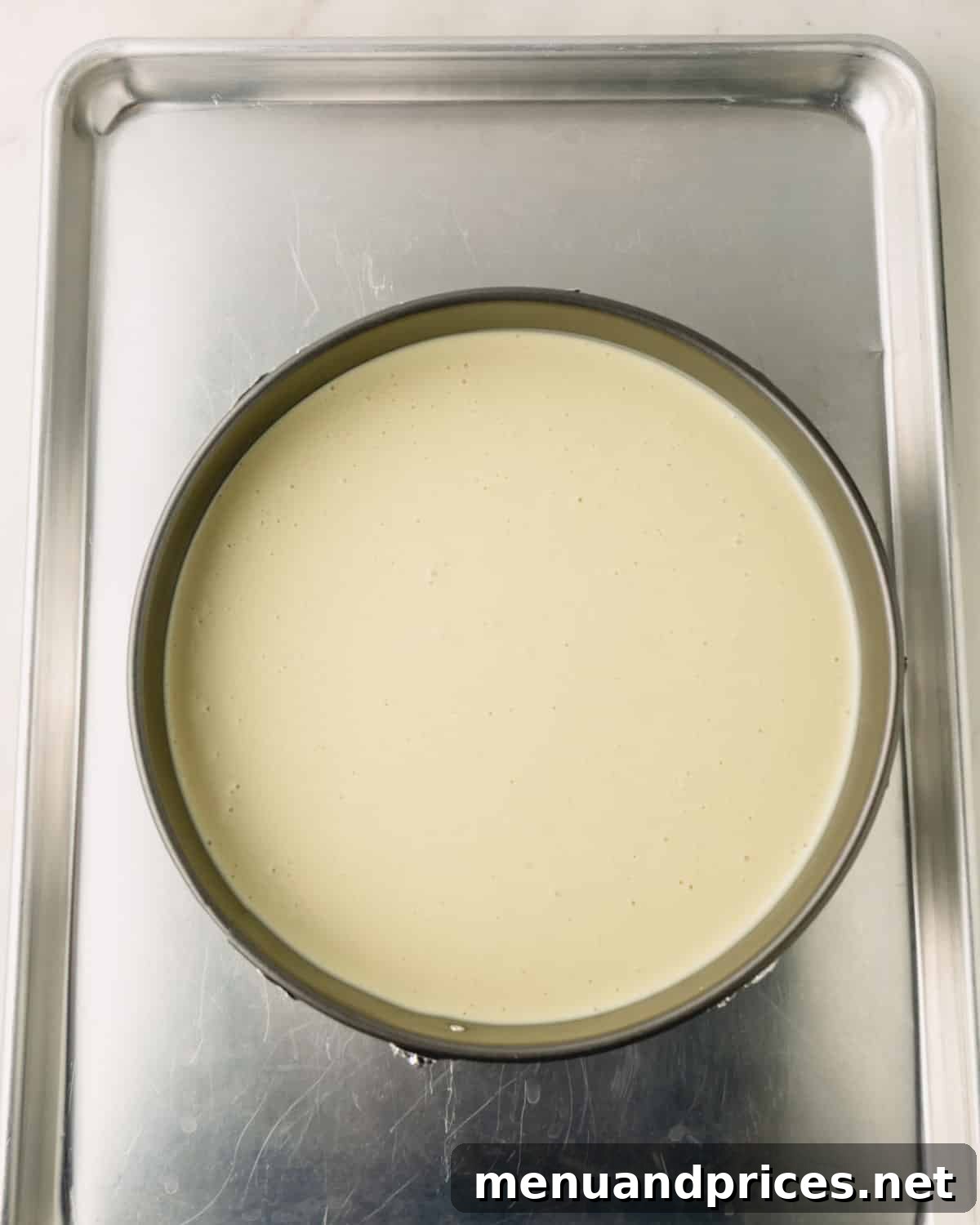 A baking sheet with a springform pan with pistachio cheesecake.