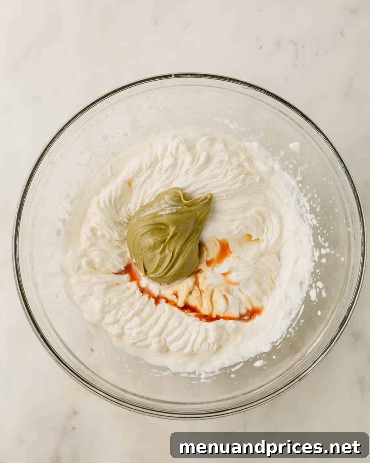A glass bowl with ingredients for pistachio whipped cream.