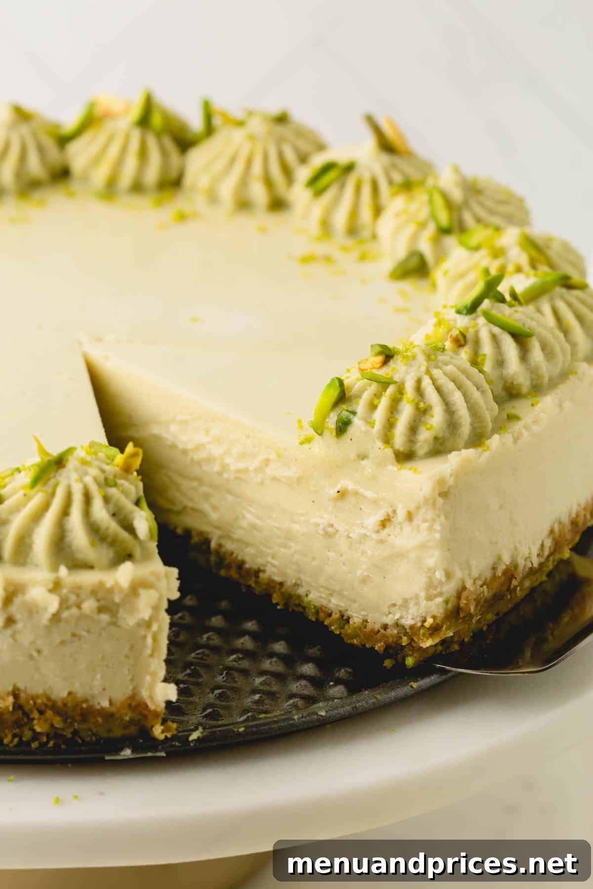 Close up image of a slice of pistachio cheesecake being removed with a cake server.