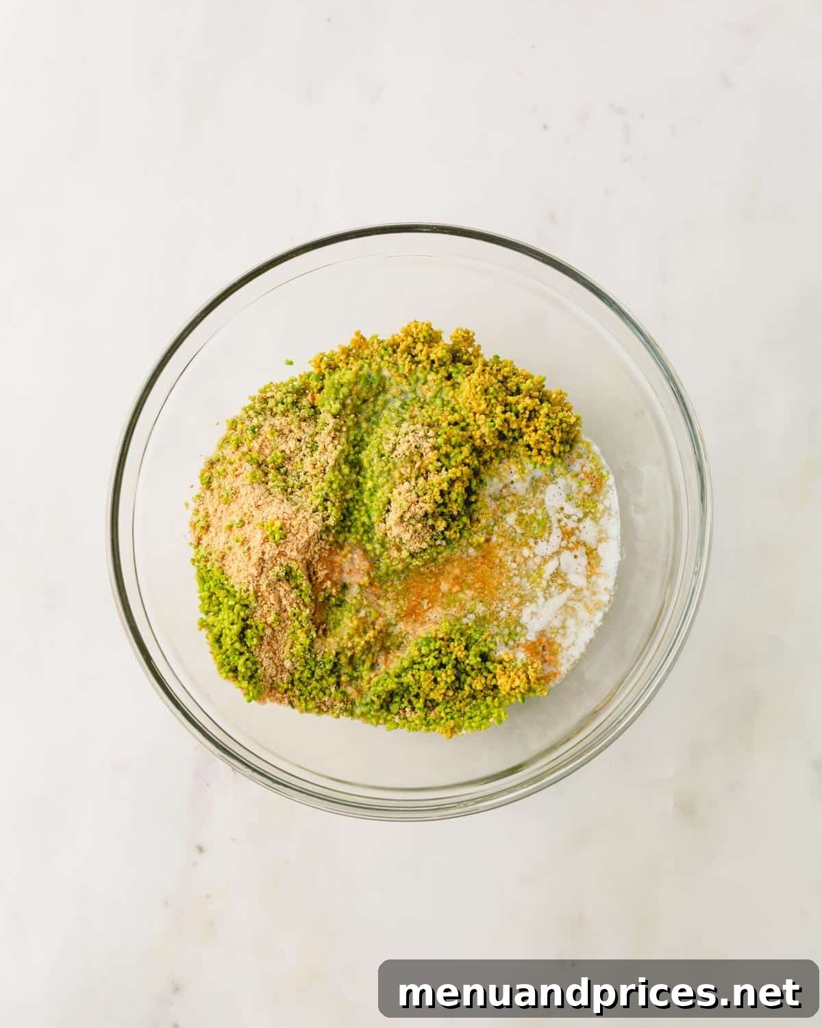 A glass bowl with ingredient for pistachio graham cracker crust.