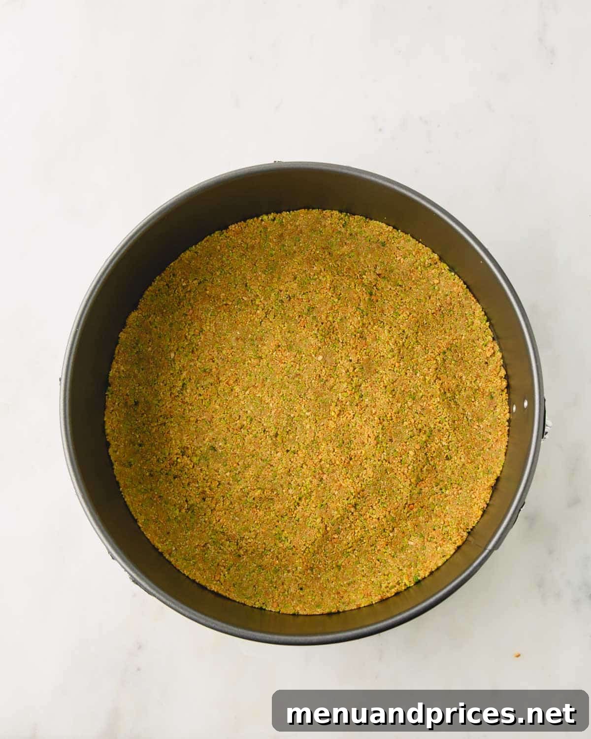 Pistachio graham cracker crust baked in a springform cake pan.