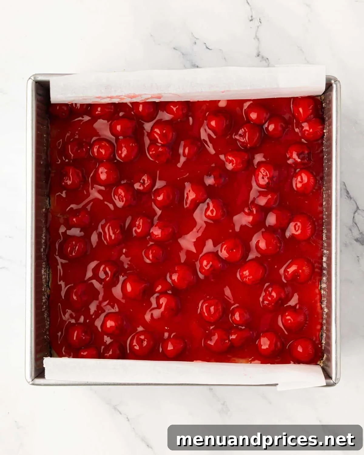 A baking pan with cherry pie bars with cookie crust and cherry pie topping.