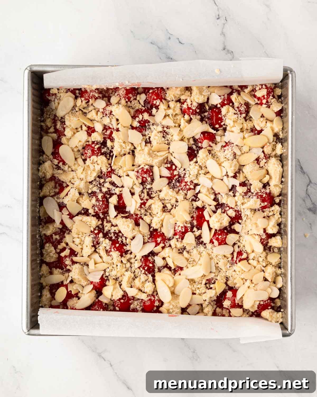 A baking pan with cherry pie bars with streusel and almond topping.