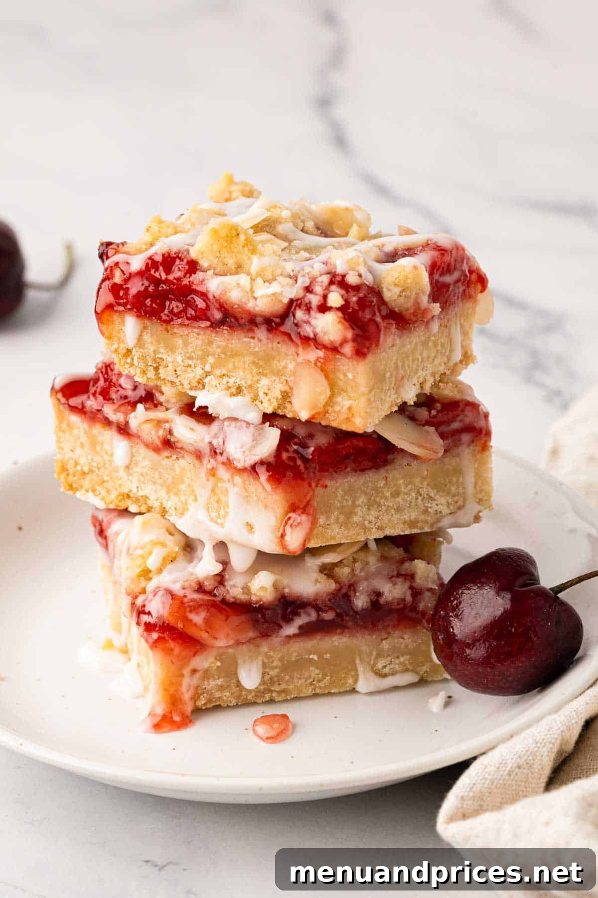 A stack of three cherry pie bars on a white plate.