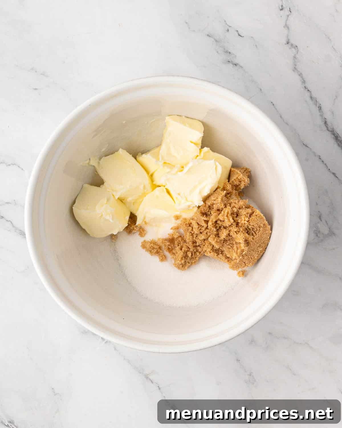A white bowl with butter, brown sugar, and regular sugar.